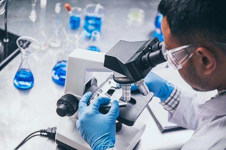 Health care researcher looking through a microscope in a lab